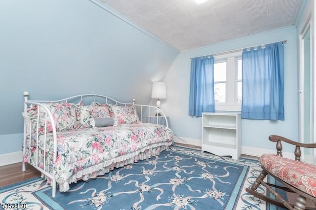 bedroom with wood finished floors, baseboards, and crown molding