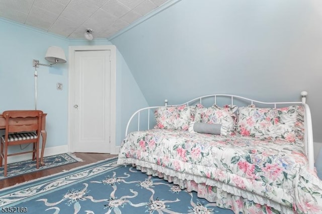 bedroom with baseboards, wood finished floors, and crown molding