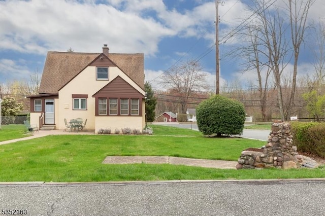 exterior space featuring a chimney, entry steps, a patio area, a yard, and stucco siding