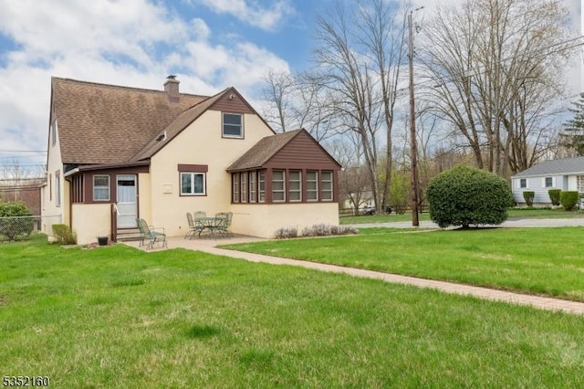 back of house with entry steps, a shingled roof, a chimney, and stucco siding