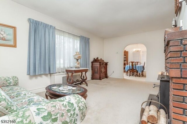 living area featuring arched walkways, carpet floors, a notable chandelier, and baseboards