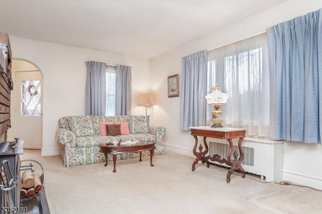 sitting room with baseboards, carpet flooring, and arched walkways