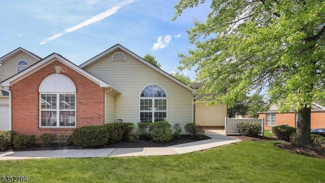 view of front facade featuring a front lawn, brick siding, and fence