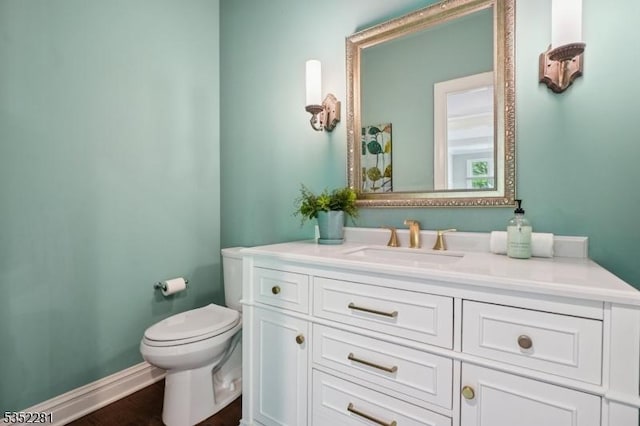 bathroom featuring toilet, vanity, and baseboards