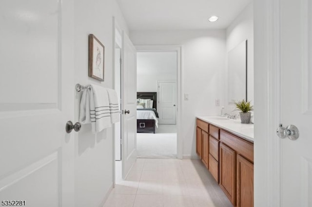 ensuite bathroom featuring double vanity, tile patterned flooring, recessed lighting, and baseboards