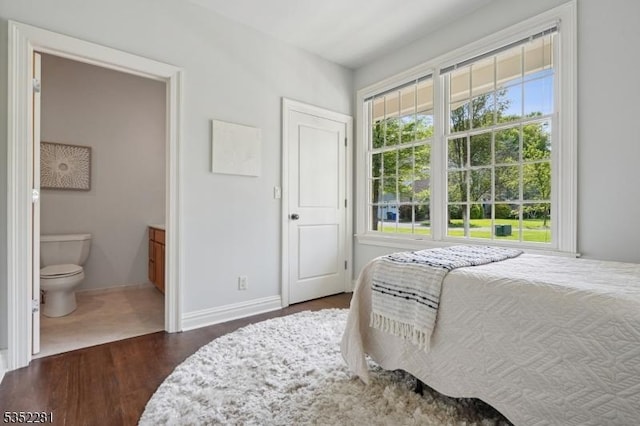 bedroom featuring wood finished floors, baseboards, and connected bathroom