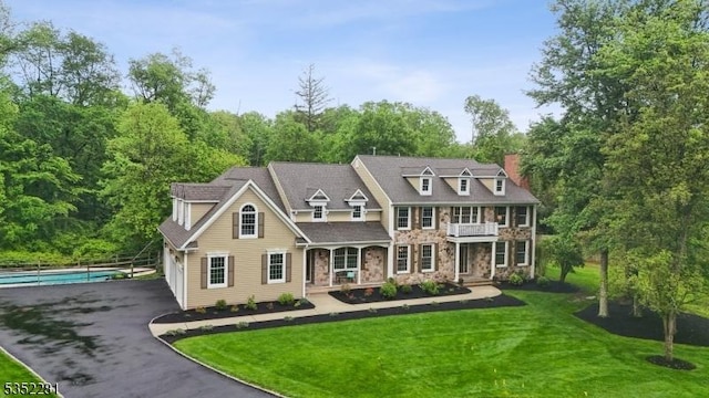 view of front of property featuring a balcony, covered porch, a chimney, and stone siding