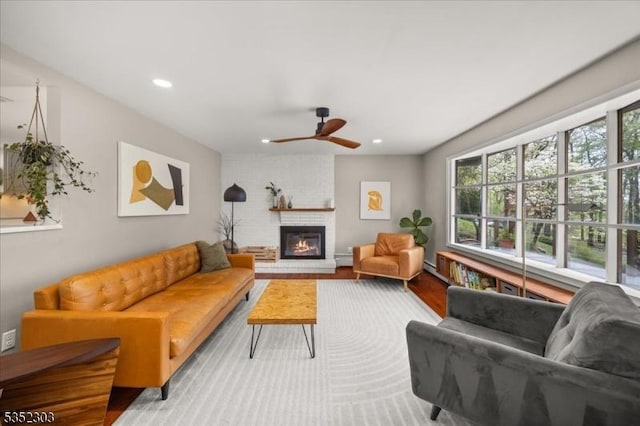 living area with recessed lighting, ceiling fan, wood finished floors, and a fireplace
