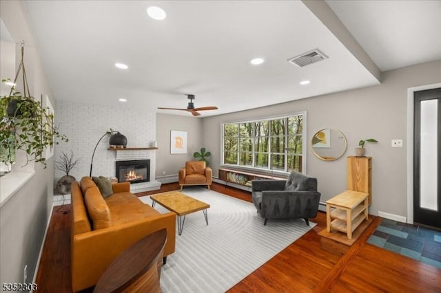 living area featuring a brick fireplace, recessed lighting, visible vents, and wood finished floors