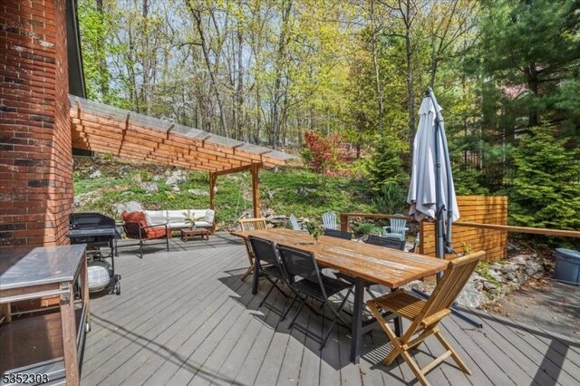 wooden terrace featuring an outdoor hangout area, outdoor dining space, grilling area, and a pergola