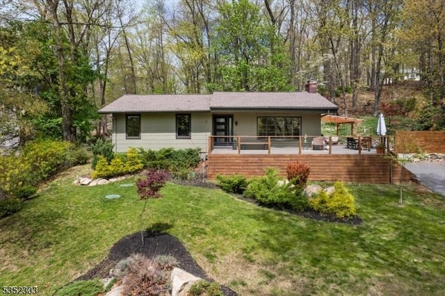 single story home featuring a front lawn, a wooden deck, and a chimney