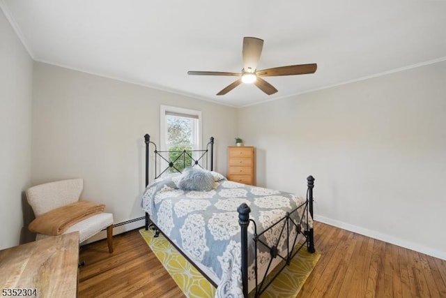 bedroom with a ceiling fan, baseboards, ornamental molding, and wood finished floors