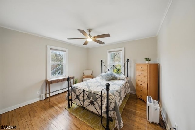 bedroom featuring crown molding, baseboards, light wood finished floors, and a baseboard radiator