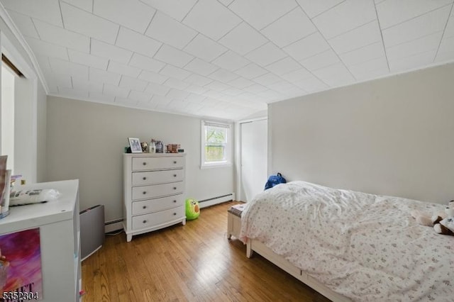 bedroom with a baseboard heating unit and wood finished floors