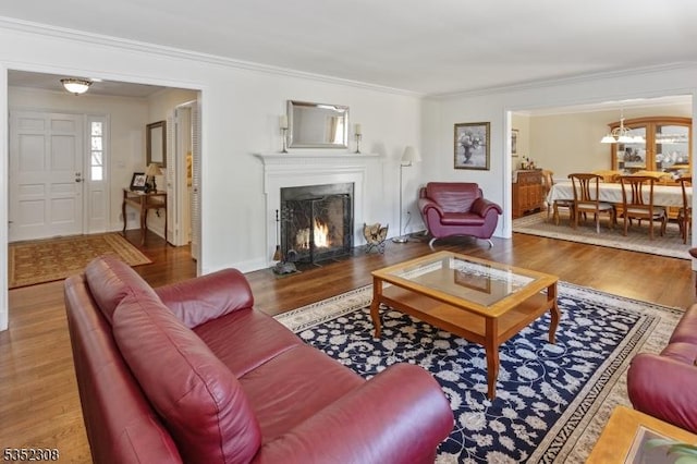 living area featuring crown molding, a fireplace with flush hearth, and wood finished floors