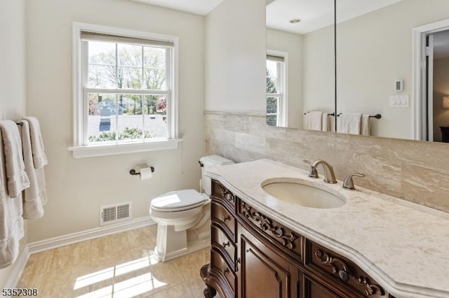 bathroom with toilet, visible vents, and a healthy amount of sunlight