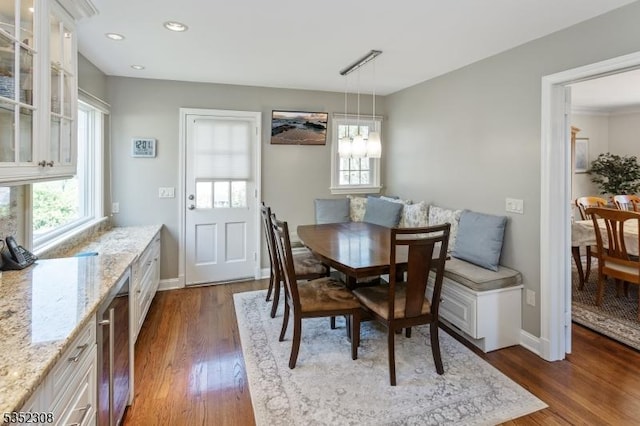 dining space featuring beverage cooler, dark wood-style flooring, and baseboards