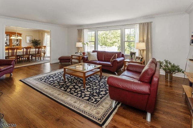 living area featuring baseboards, an inviting chandelier, ornamental molding, and wood finished floors