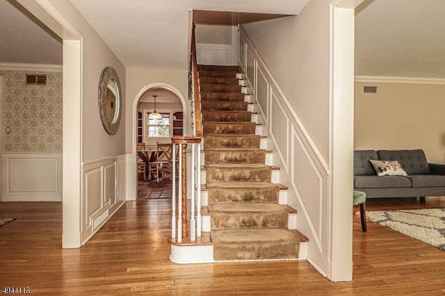 1775 Sleepy Hollow Ln, Plainfield City, NJ 07060 - stairs featuring wood-type flooring, a decorative wall, wainscoting, ornamental molding, and arched walkways
