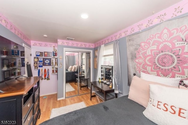 bedroom featuring baseboards, visible vents, light wood-style floors, and a closet