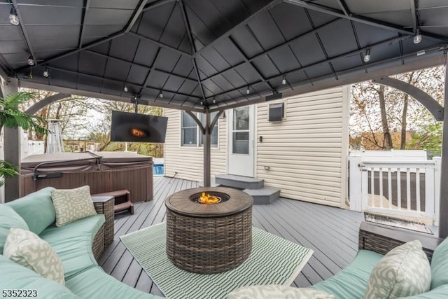 wooden deck featuring a gazebo, a hot tub, and an outdoor living space with a fire pit