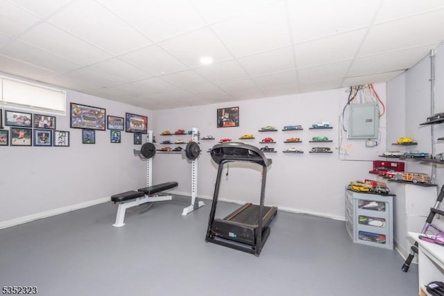 exercise area with baseboards, electric panel, and a paneled ceiling