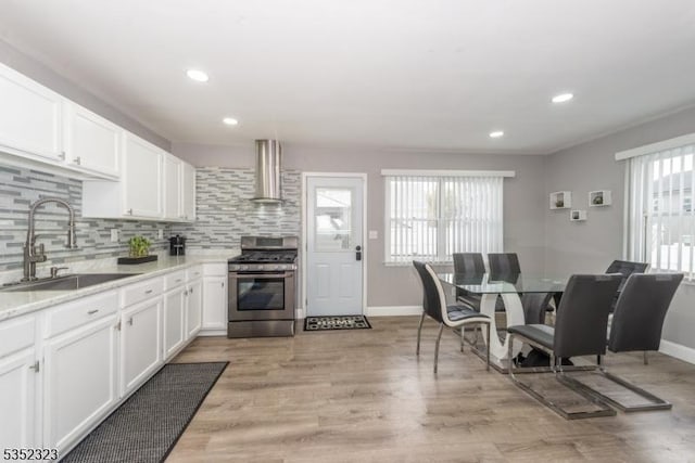 kitchen with white cabinets, a sink, baseboards, stainless steel range with gas stovetop, and extractor fan