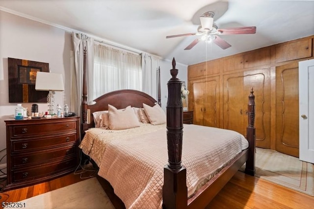 bedroom with light wood-type flooring, a ceiling fan, and ornamental molding