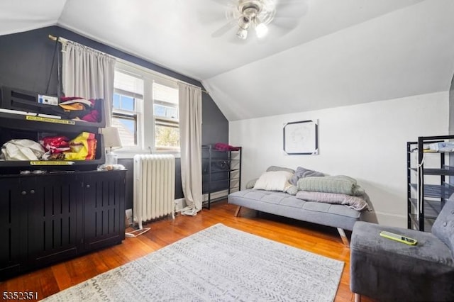 bedroom featuring lofted ceiling, ceiling fan, baseboards, radiator heating unit, and wood finished floors