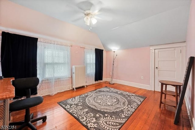 sitting room with lofted ceiling, hardwood / wood-style flooring, ceiling fan, baseboards, and radiator heating unit