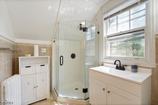 bathroom featuring radiator heating unit, vanity, a shower stall, and vaulted ceiling