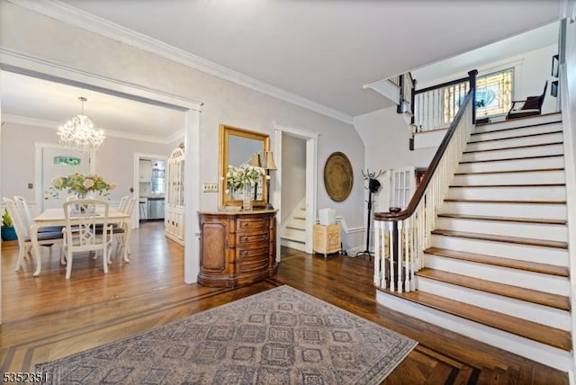 foyer with stairway, wood finished floors, an inviting chandelier, and crown molding