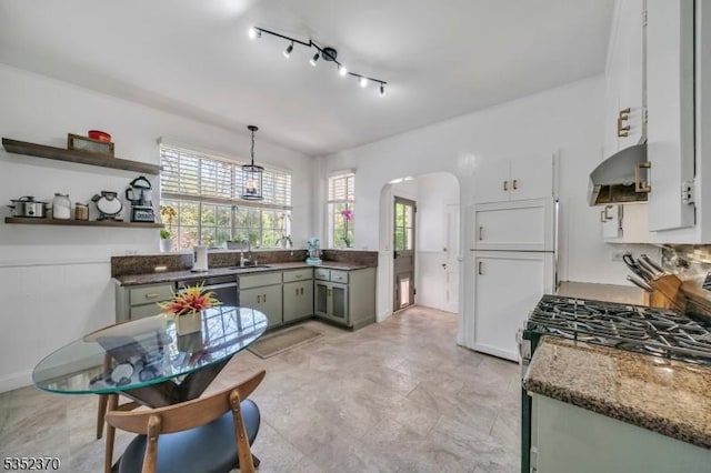 kitchen with a sink, arched walkways, stainless steel range with gas stovetop, and a healthy amount of sunlight
