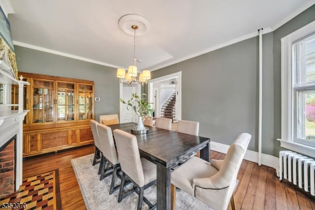 dining space with radiator heating unit, crown molding, dark wood-style floors, and a notable chandelier