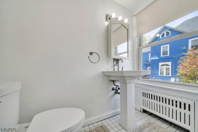 bathroom featuring radiator, tile patterned floors, baseboards, and toilet