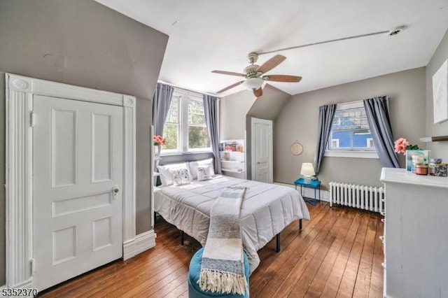 bedroom with radiator, a ceiling fan, baseboards, vaulted ceiling, and hardwood / wood-style flooring