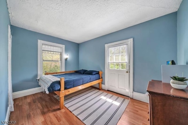 bedroom featuring a textured ceiling, baseboards, and wood finished floors