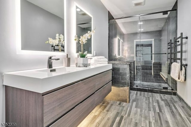 bathroom featuring vanity, a shower stall, wood finished floors, and visible vents