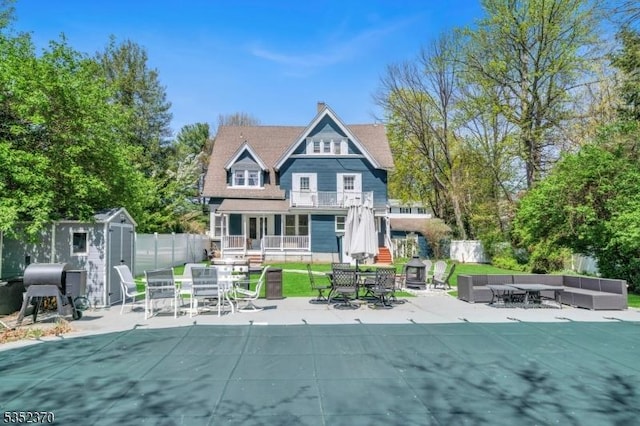 rear view of property featuring outdoor lounge area, outdoor dining area, a patio area, and a storage unit