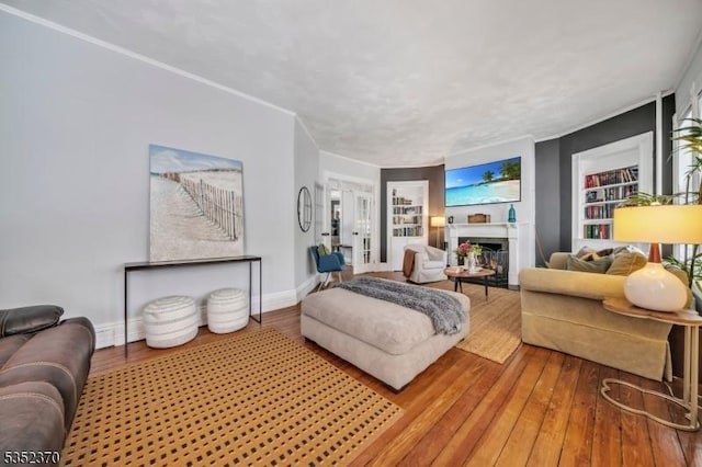 living room with baseboards, built in shelves, light wood finished floors, and a fireplace