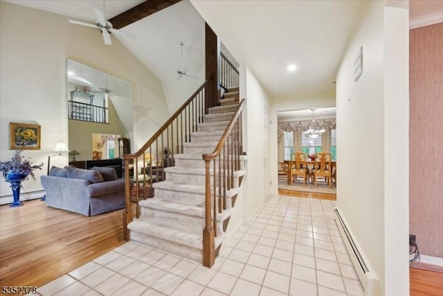 staircase with a baseboard heating unit, ceiling fan, beamed ceiling, wood finished floors, and baseboards