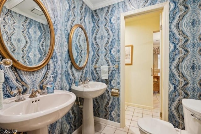 bathroom with toilet, wallpapered walls, a sink, baseboards, and tile patterned flooring