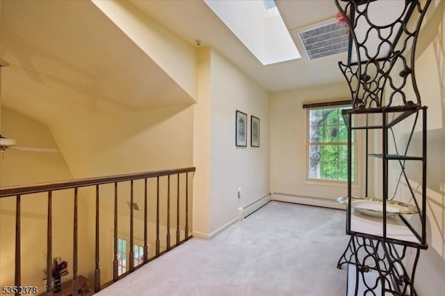 hallway featuring a skylight, carpet, and baseboards