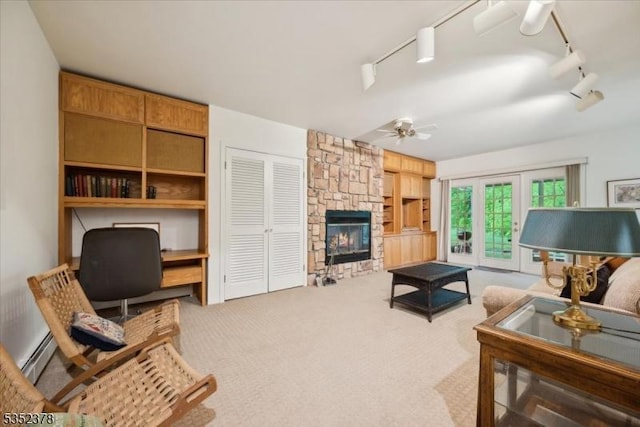 living area with ceiling fan, a fireplace, built in features, carpet flooring, and rail lighting