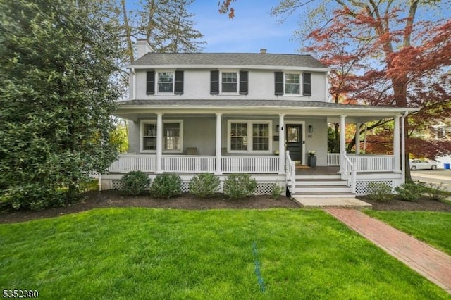 farmhouse inspired home featuring covered porch, stucco siding, a chimney, and a front yard