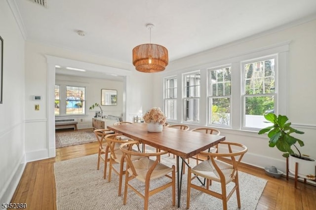 dining space featuring crown molding, baseboards, plenty of natural light, and light wood finished floors