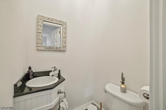bathroom with toilet, baseboards, and vanity