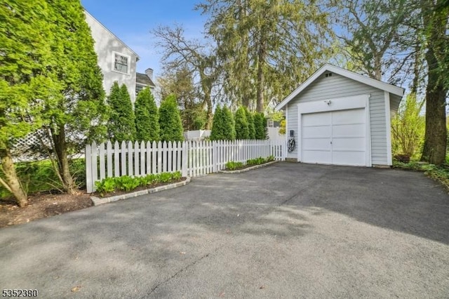 detached garage with fence and aphalt driveway