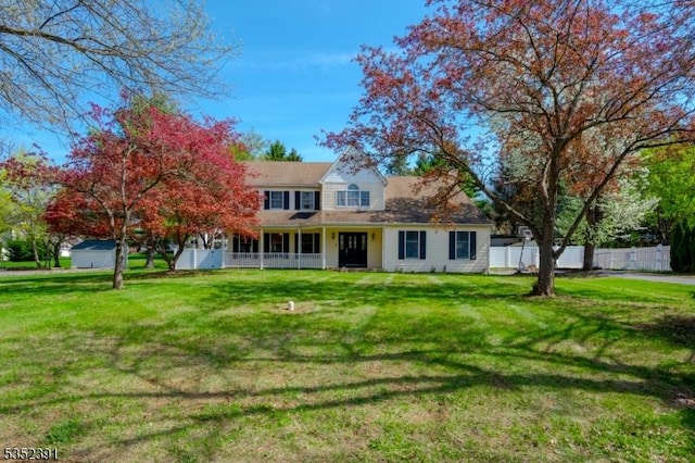 rear view of property featuring fence, a yard, and a porch