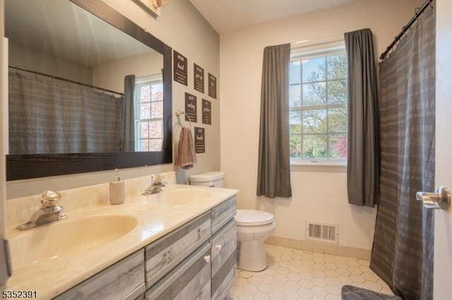 full bath featuring visible vents, toilet, double vanity, and a sink